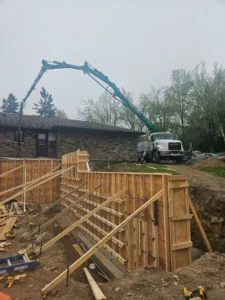 20 metre Concrete boom pump truck pouring concrete into tall wall formwork during foundation construction for a residential project in Ontario, demonstrating proper placement and form setup.