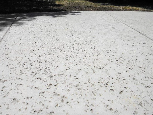 Concrete surface with small pitted marks left by a salt finish technique, offering subtle texture and improved grip.