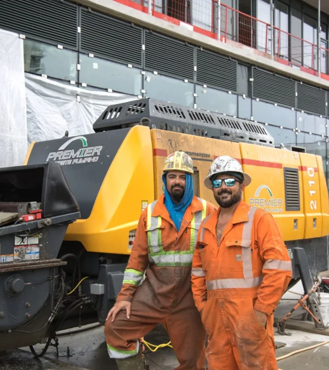 Two crew members standing beside the Premier Concrete Pumping pump Unit 2110